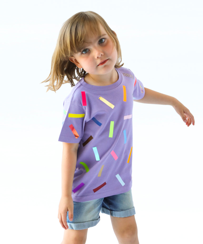Child wearing a purple cotton t-shirt with colorful sprinkle confetti pattern