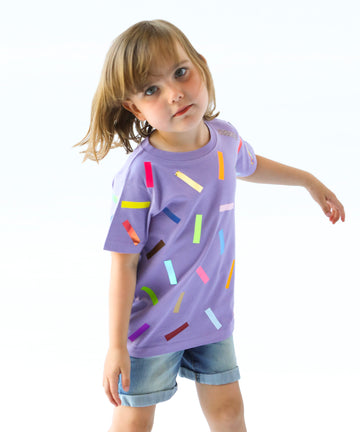Child wearing a purple cotton t-shirt with colorful sprinkle confetti pattern