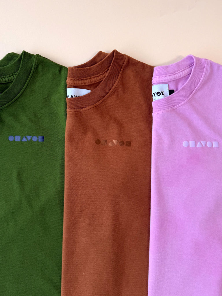 Three 100% cotton tshirts in green, brown, and pink with the tonal 'okayok' Bauhaus shape logo