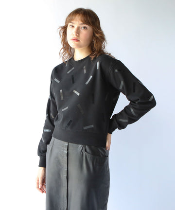 a woman wears a cotton sweatshirt in black with black confetti sprinkle graphic print
