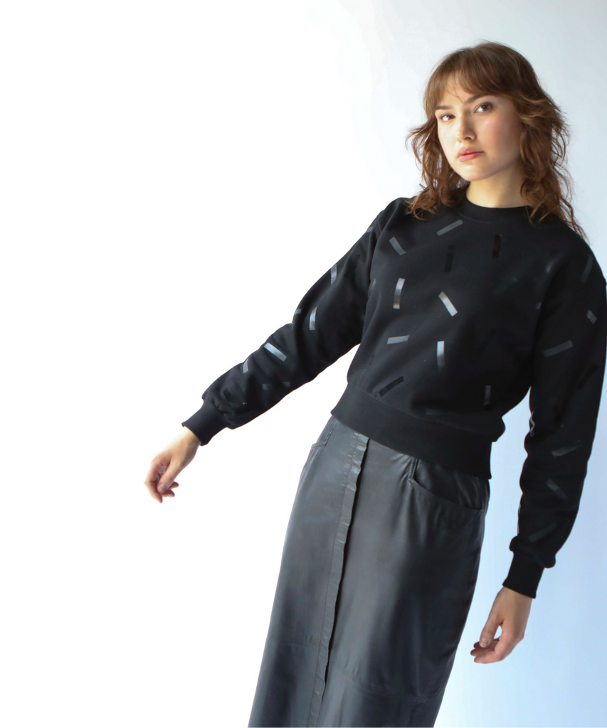 a woman wears a cotton sweatshirt in black with black confetti sprinkle graphic print