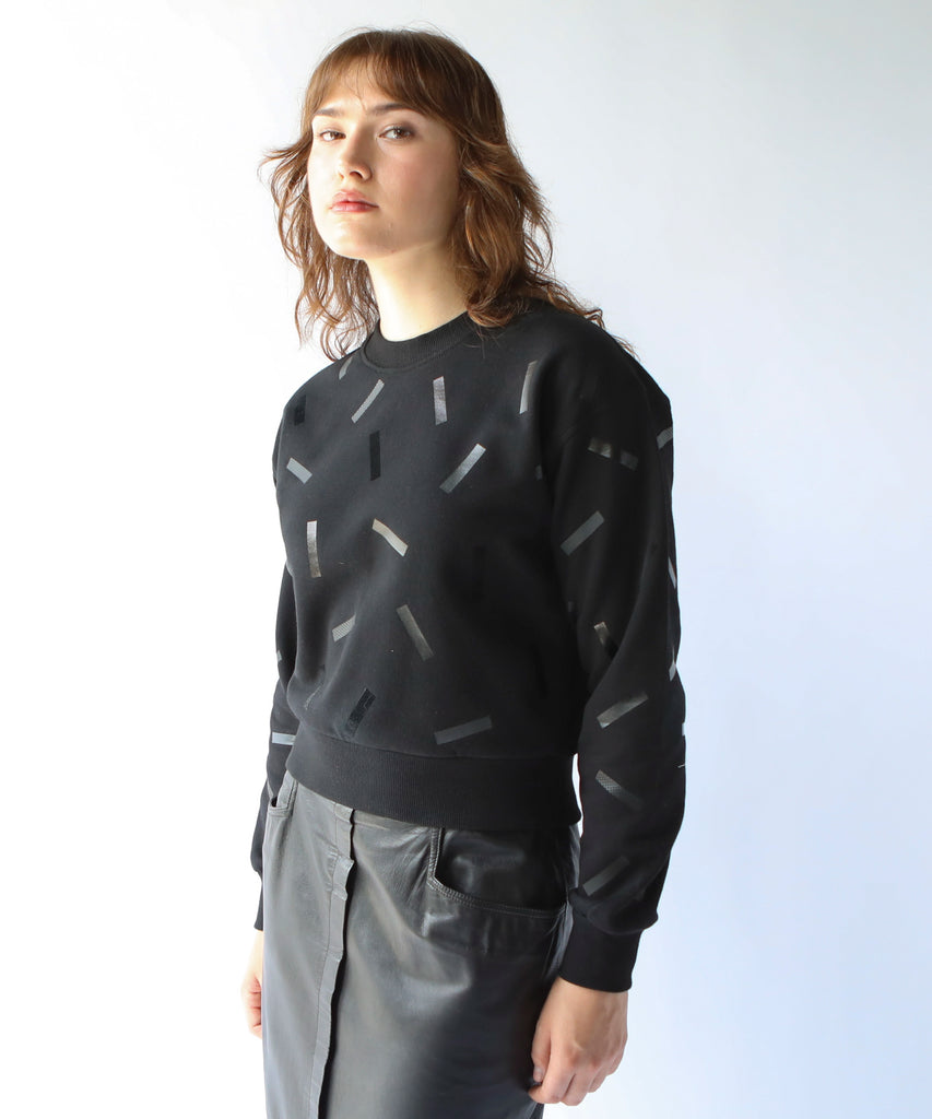 a woman wears a cotton sweatshirt in black with black confetti sprinkle graphic print