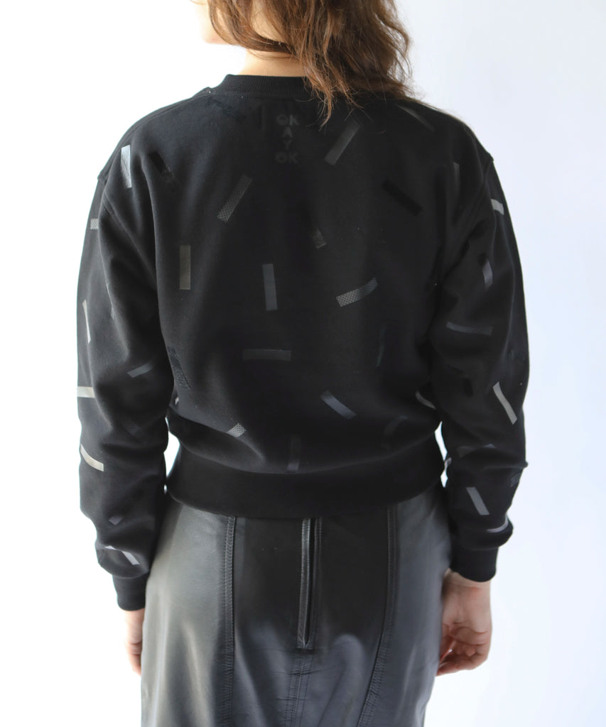 the back of a woman in a cotton sweatshirt in black with black confetti sprinkle graphic print
