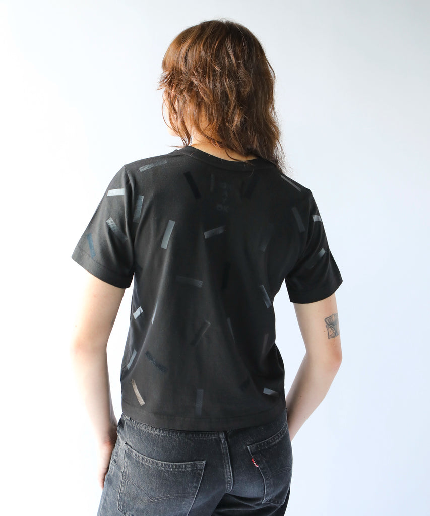 a woman wears a boxy cotton tshirt in black with black confetti sprinkle graphic print