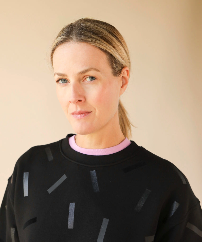 a woman wears a cotton sweatshirt in black with black confetti sprinkle graphic print