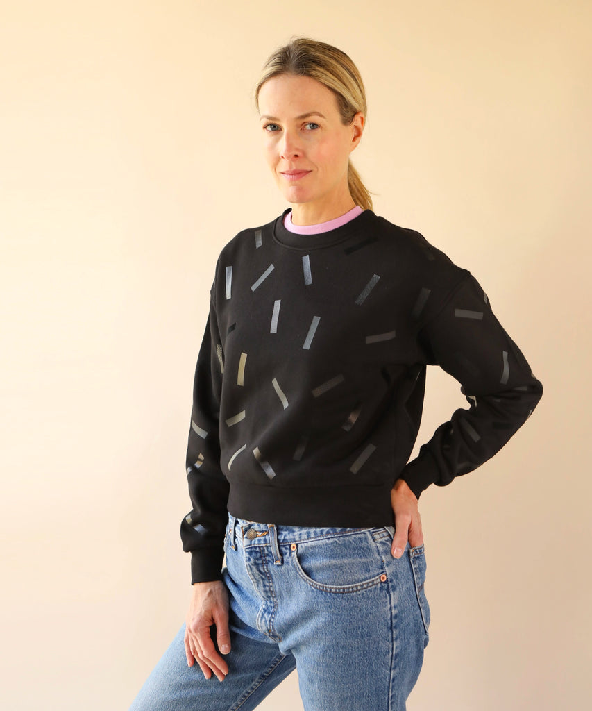 a woman wears a cotton sweatshirt in black with black confetti sprinkle graphic print