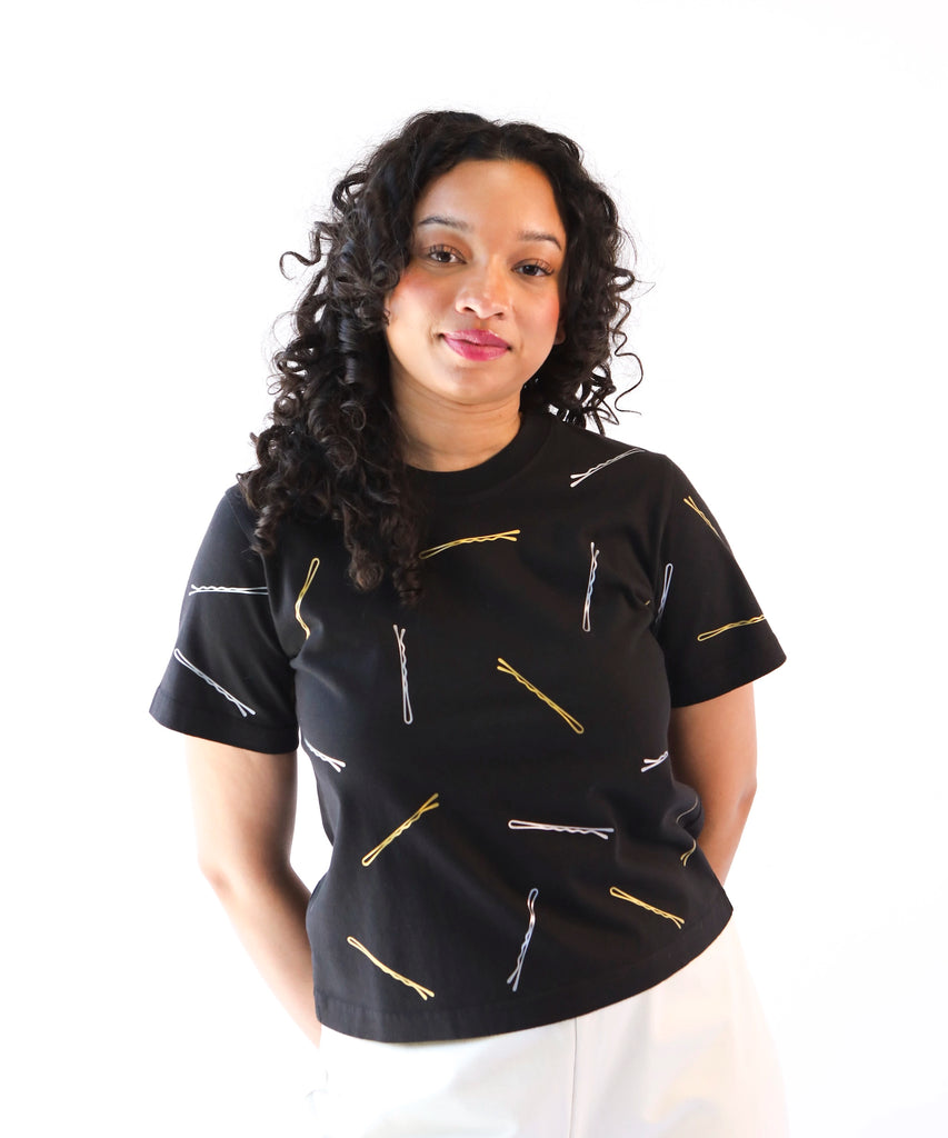 Woman wearing a black cotton t-shirt with gold and silver bobby pin pattern