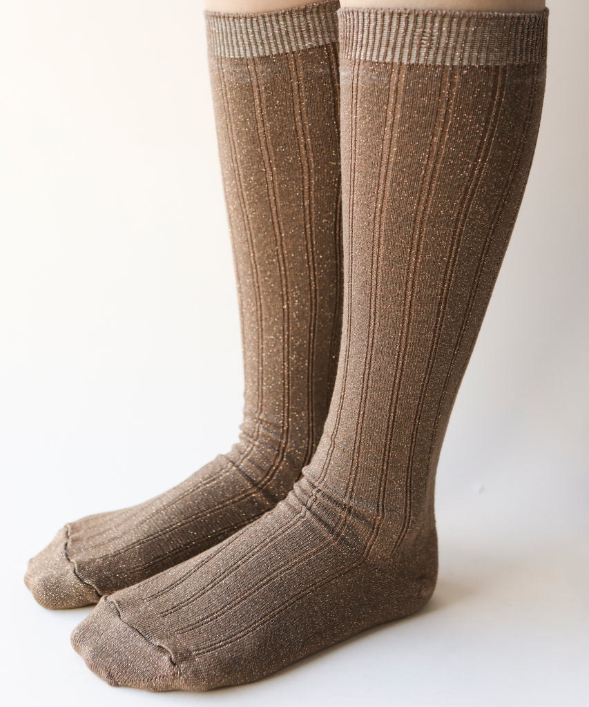 A side view of pair of cotton and nylon knee highs in a sparkly copper colour worn on a model