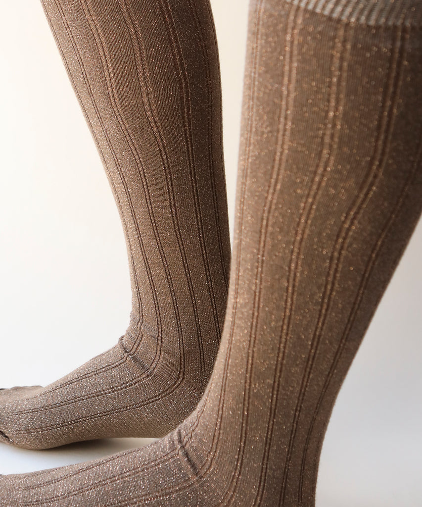 A close up of a pair of cotton and nylon knee highs in a sparkly copper colour worn on a model