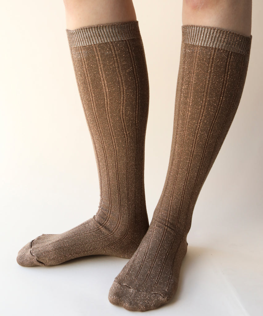 A front view of a pair of cotton and nylon knee highs in a sparkly copper colour worn on a model