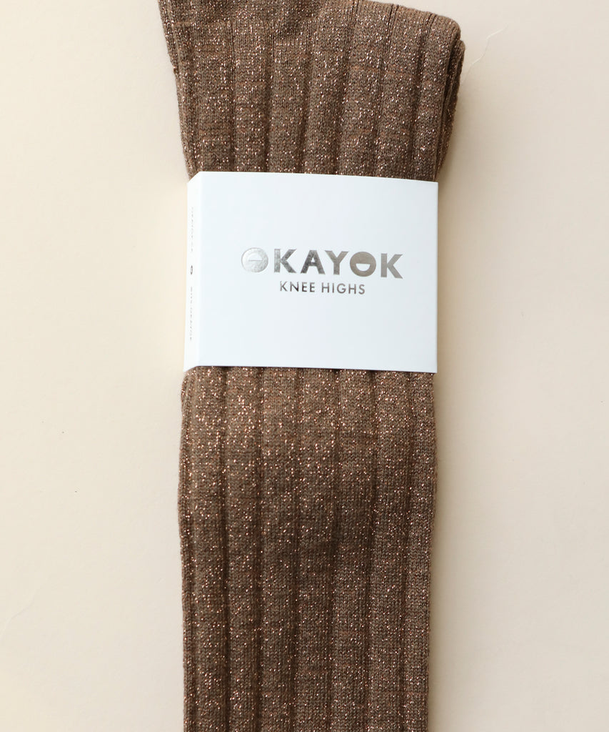 A pair of cotton and nylon knee highs in a sparkly copper colour with a white label on a beige background