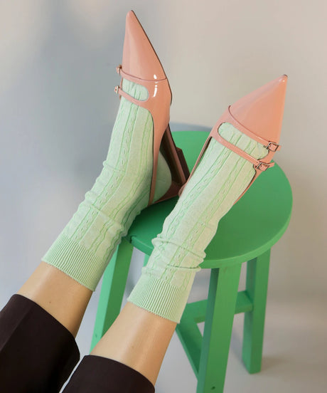 A pair of unisex, lightweight cable dressy cotton socks in pale green made in Canada by Toronto brand OkayOk styled with patent leather kitten heels in nude