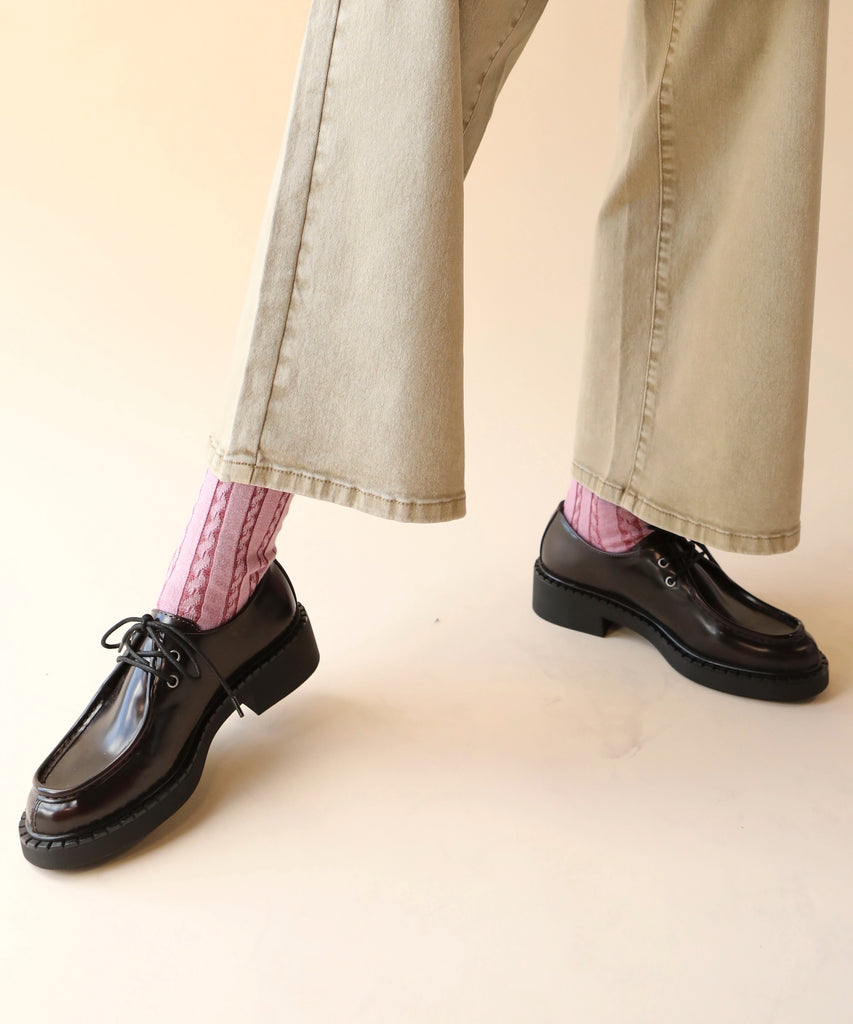 Person wearing loafer shoes and pink cable knitted socks 
