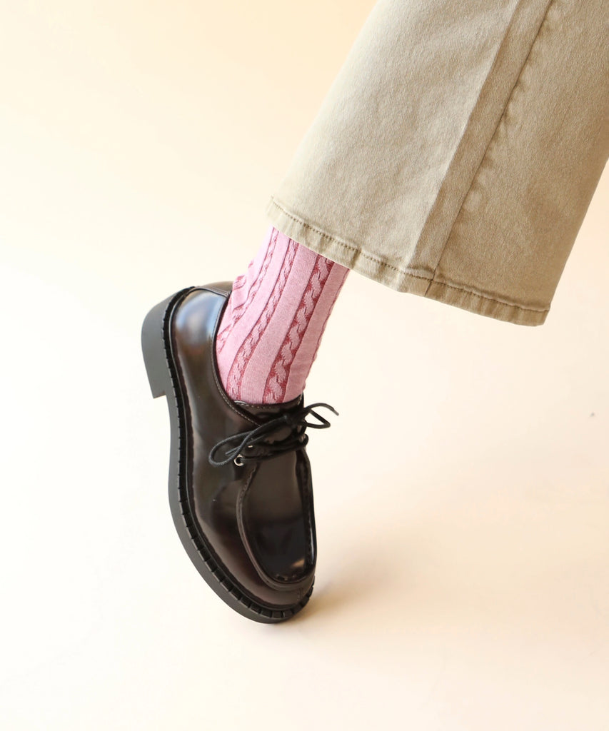 Person wearing loafer shoes and pink cable knitted socks 