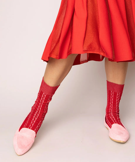 A pair of unisex, lightweight cable dressy cotton socks in red made in Canada by Toronto brand OkayOk styled with pale pink shoes