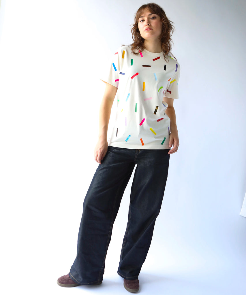 Woman wearing a cream cotton t-shirt with colorful confetti sprinkle pattern on it  and black cotton pants