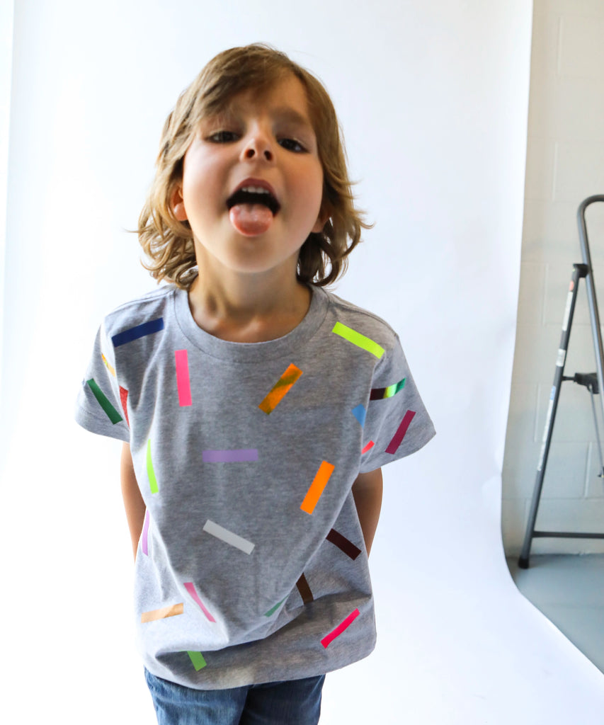 Child wearing a gray cotton t-shirt with colorful sprinkle confetti pattern