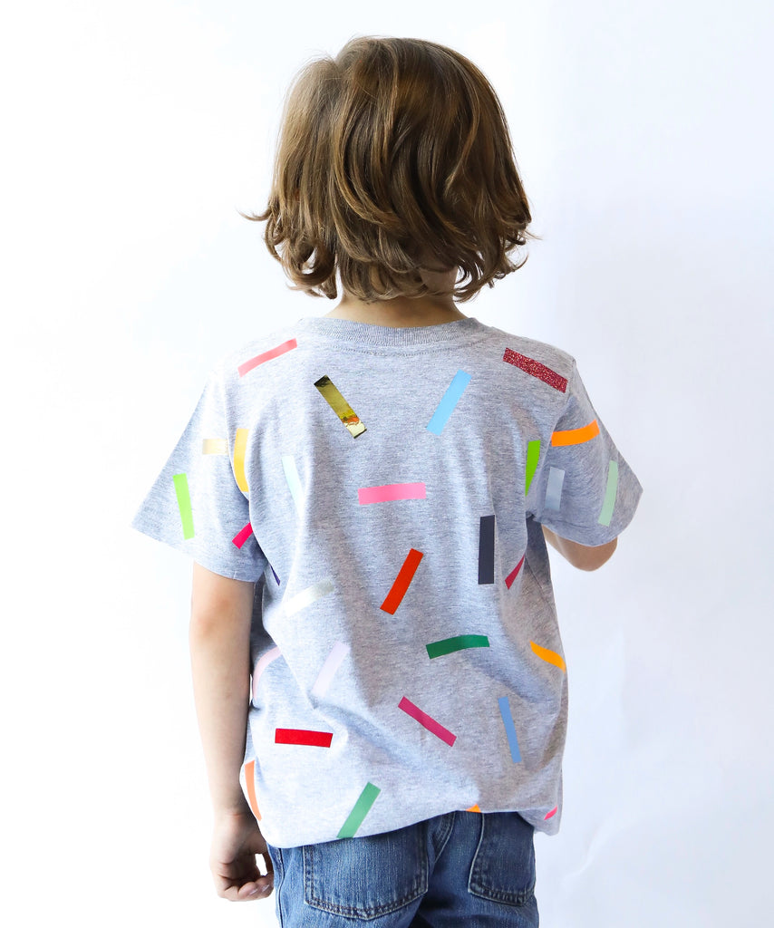 Child wearing a gray cotton t-shirt with colorful sprinkle confetti pattern