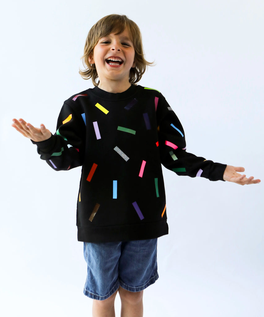 a child wearing cotton sweatshirt in black with colourful confetti sprinkle pattern 