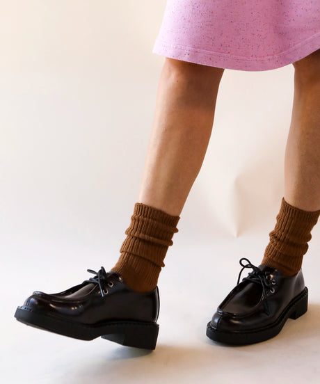 A person wearing a pair of unisex ribbed crew cotton socks in tobacco brown made in Canada by Toronto brand OkayOk with loafers