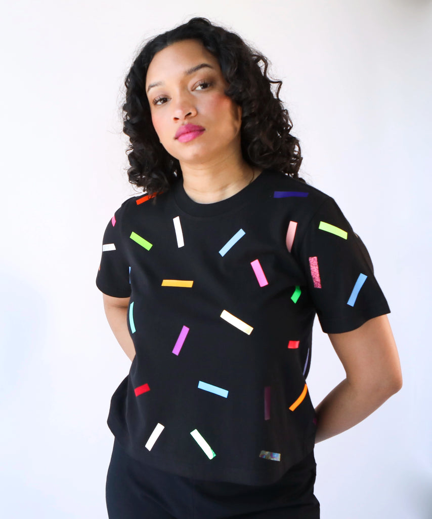 A woman wearing a cotton t-shirt with colorful confetti sprinkles pattern in black