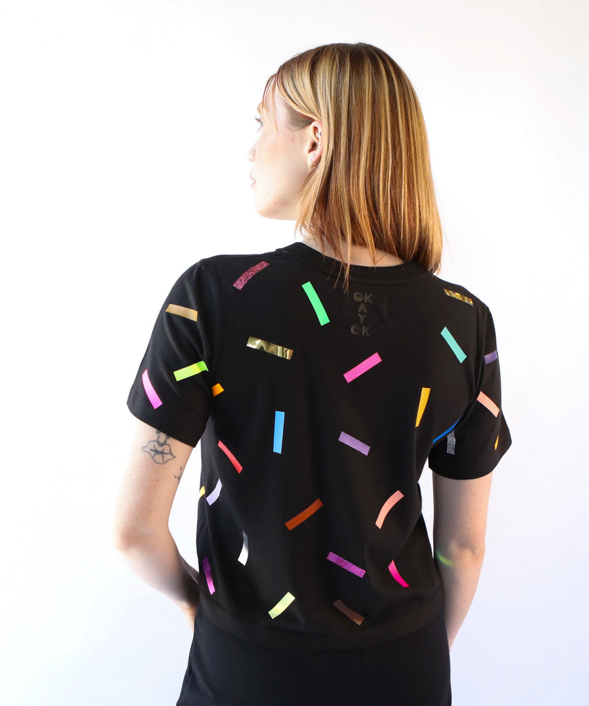 A woman wearing a cotton t-shirt with colorful confetti sprinkles pattern in black