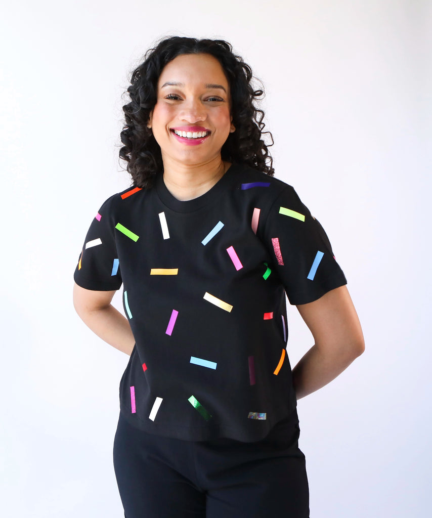 A woman wearing a cotton t-shirt with colorful confetti sprinkles pattern in black