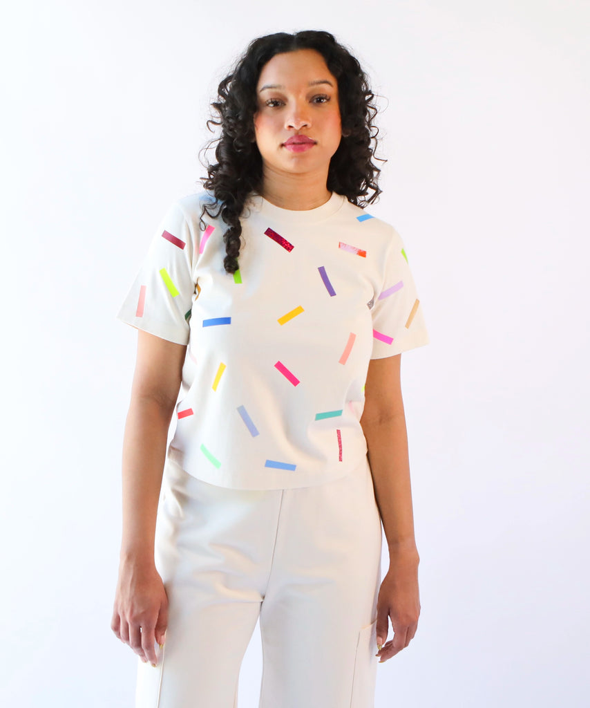 a woman wearing a cotton t-shirt with colorful confetti sprinkles pattern in cream