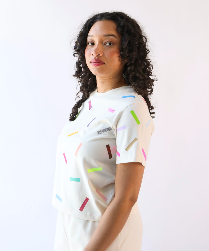 a woman wearing a cotton t-shirt with colorful confetti sprinkles pattern in cream