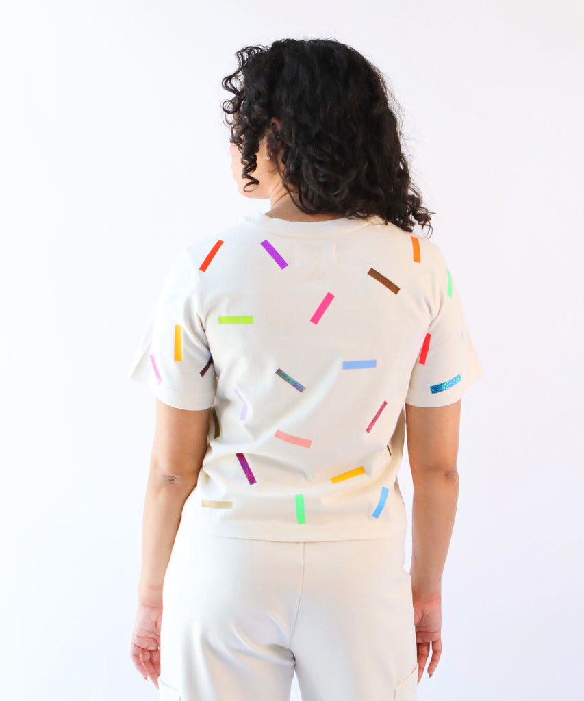 a woman wearing a cotton t-shirt with colorful confetti sprinkles pattern in cream
