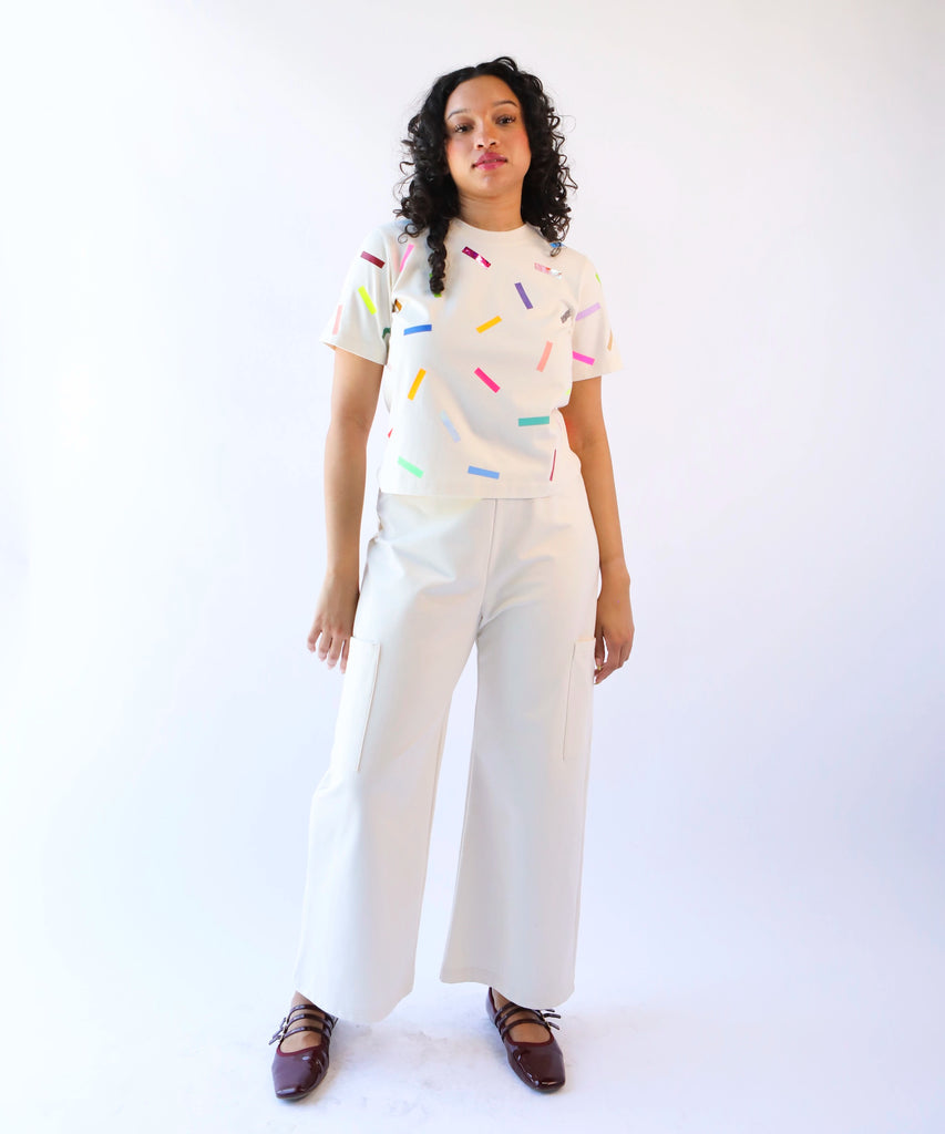 a woman wearing a cotton t-shirt with colorful confetti sprinkles pattern in cream