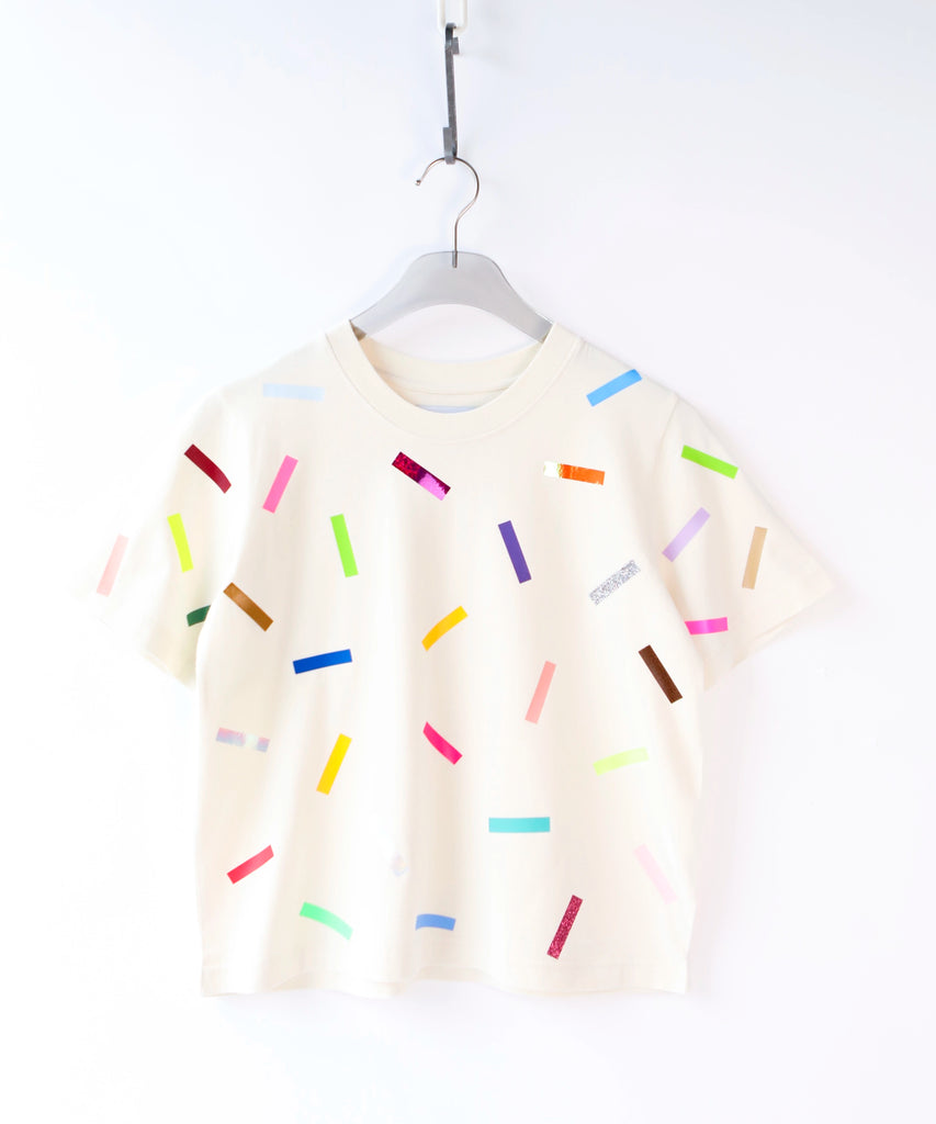 a woman wearing a cotton t-shirt with colorful confetti sprinkles pattern in cream