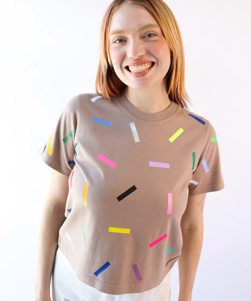 a woman wearing a taupe cotton t-shirt with colorful confetti sprinkles pattern in beige