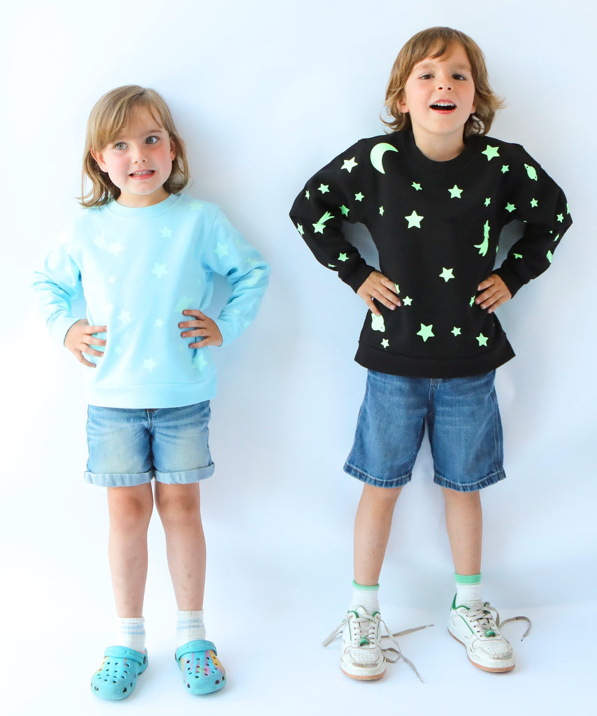 two kids wearing glow in the dark star printed cotton sweatshirt in light blue and black