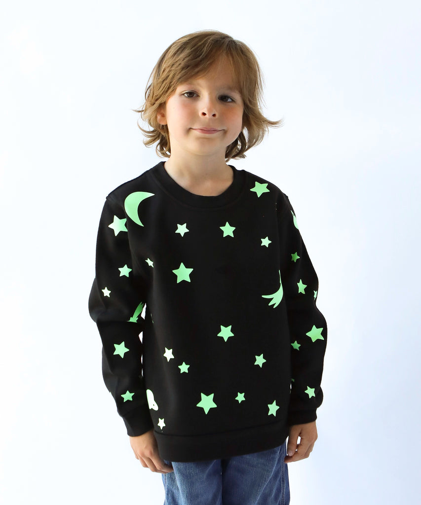child wearing glow in the dark star and moon printed cotton sweatshirt in black