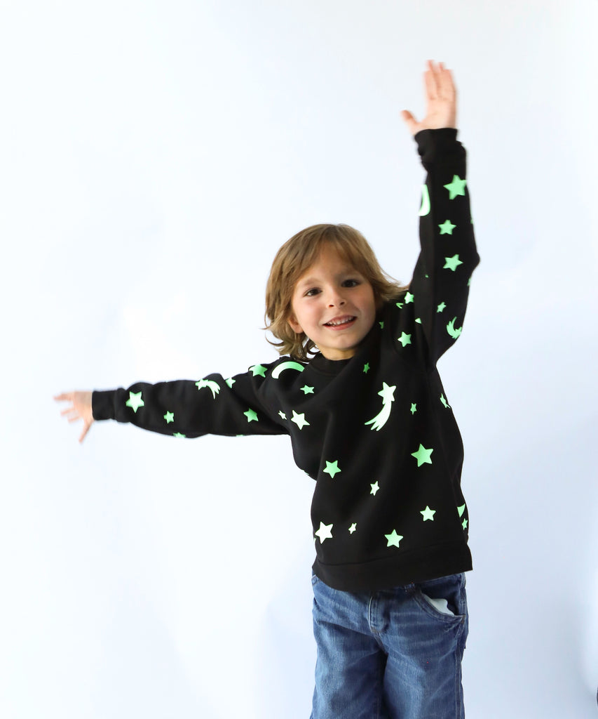 child wearing glow in the dark star and moon printed cotton sweatshirt in black