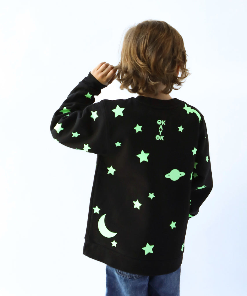 child wearing glow in the dark star and moon printed cotton sweatshirt in black