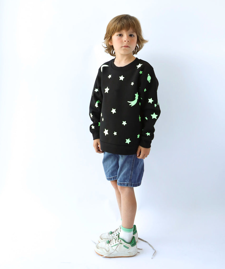 child wearing glow in the dark star and moon printed cotton sweatshirt in black