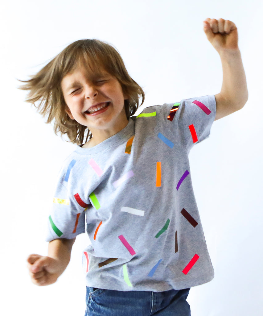 Child wearing a gray cotton t-shirt with colorful sprinkle confetti pattern