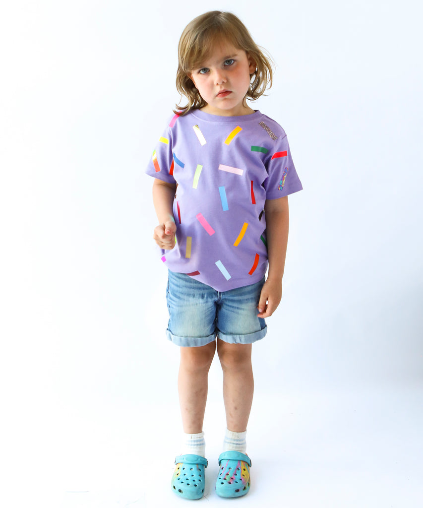 Child wearing a purple cotton t-shirt with colorful sprinkle confetti pattern