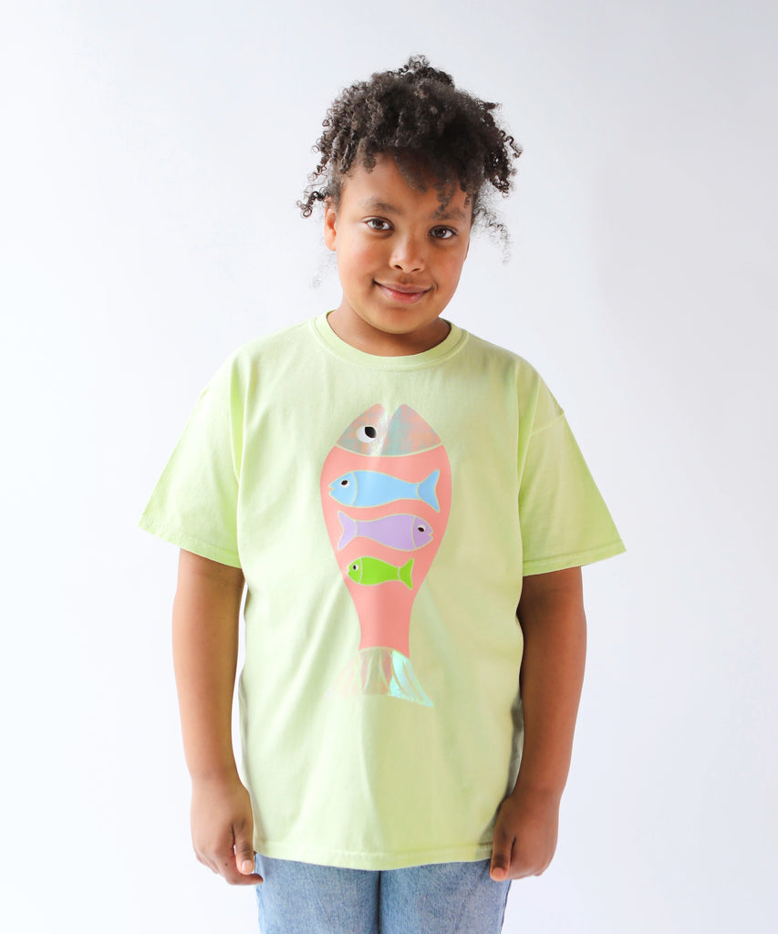 Child wearing a light green cotton t-shirt with a colorful fish design in pastel colours