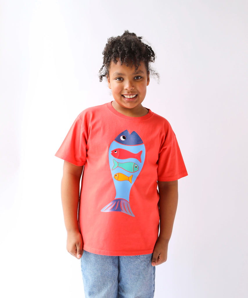 Child wearing a coral red cotton t-shirt with a colorful fish design 