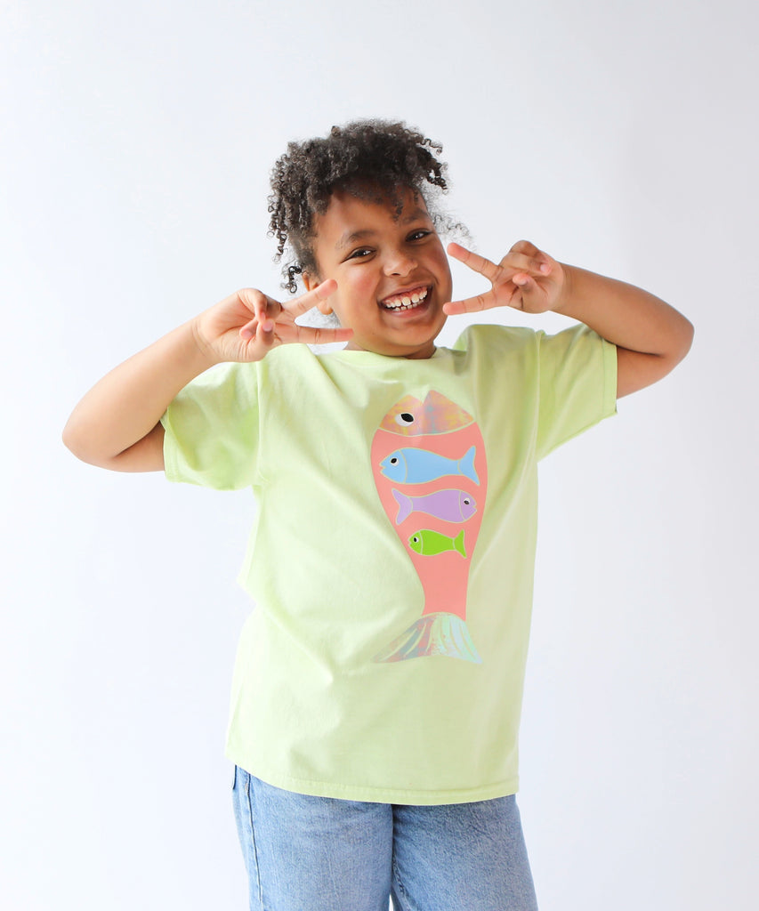 Child wearing a light green cotton t-shirt with a colorful fish design in pastel colours