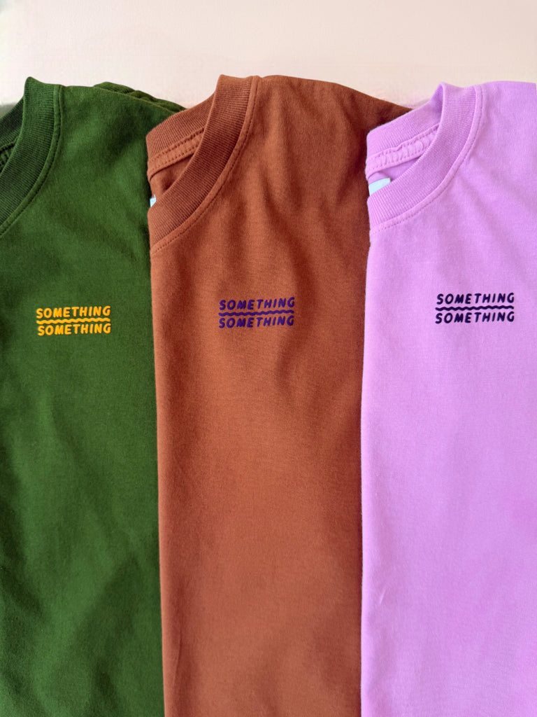 Three 100% cotton tshirts in green, brown, and pink with a little 'something something' graphic with a squiggle line