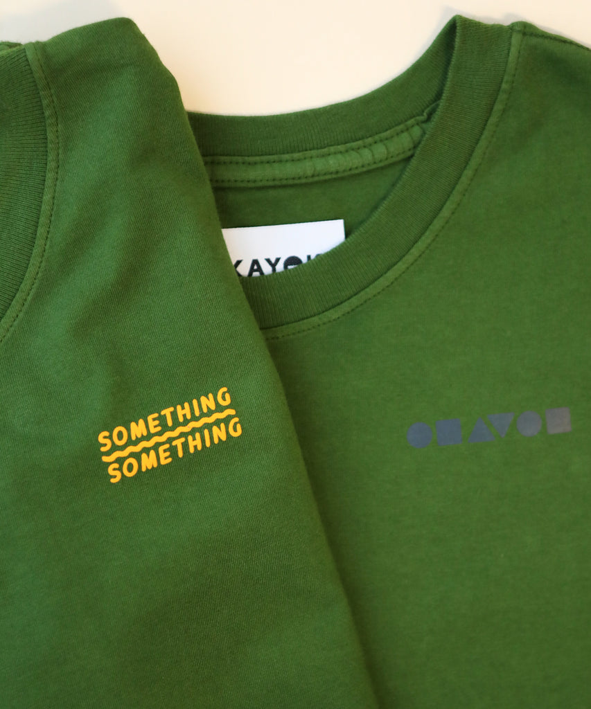 Green t-shirt with 'SOMETHING SOMETHING' text and brand logo on a white background