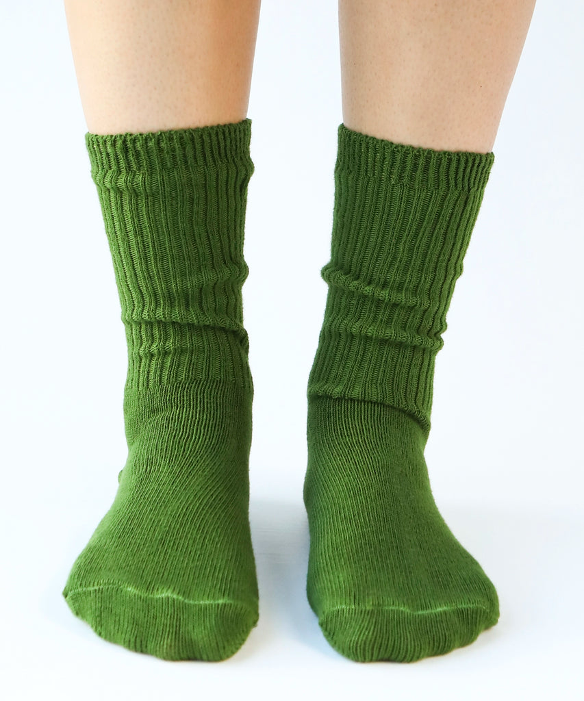 a pair of cotton socks in moss green being modeled on feet