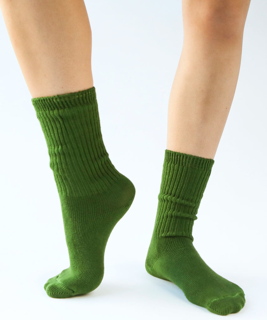 a pair of cotton socks in moss green being modeled on feet