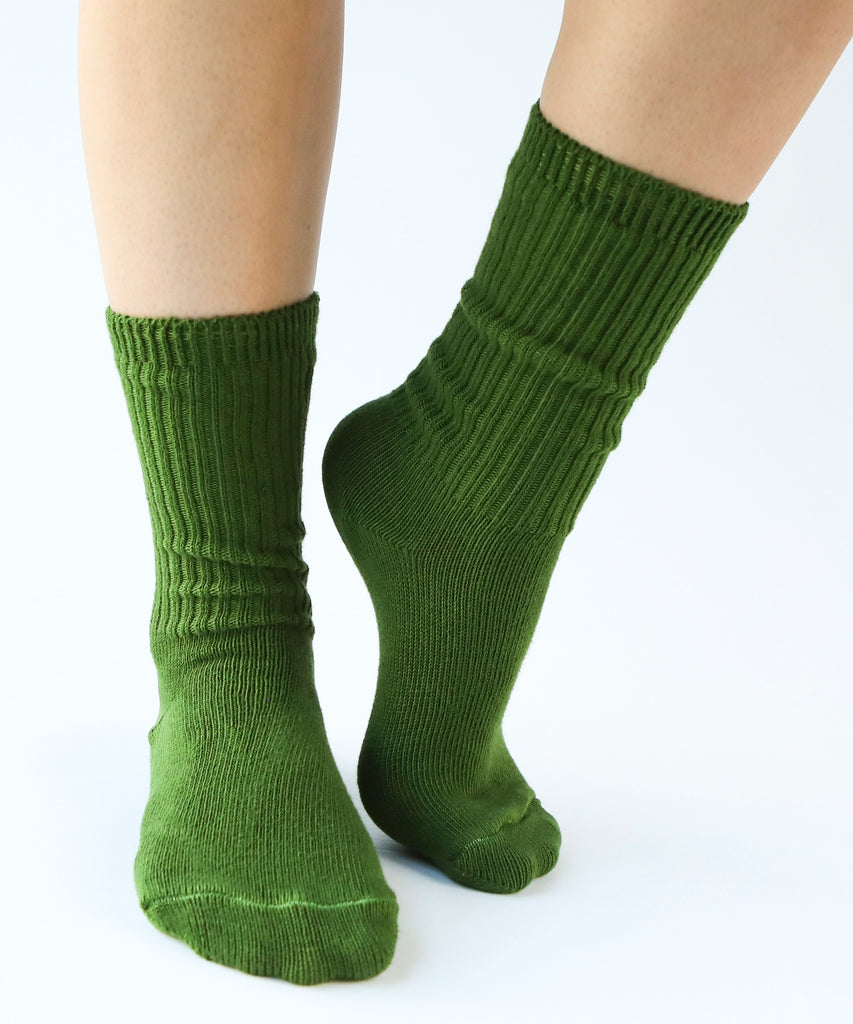 a pair of cotton socks in moss green being modeled on feet