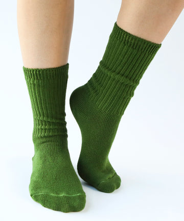 a pair of cotton socks in moss green being modeled on feet