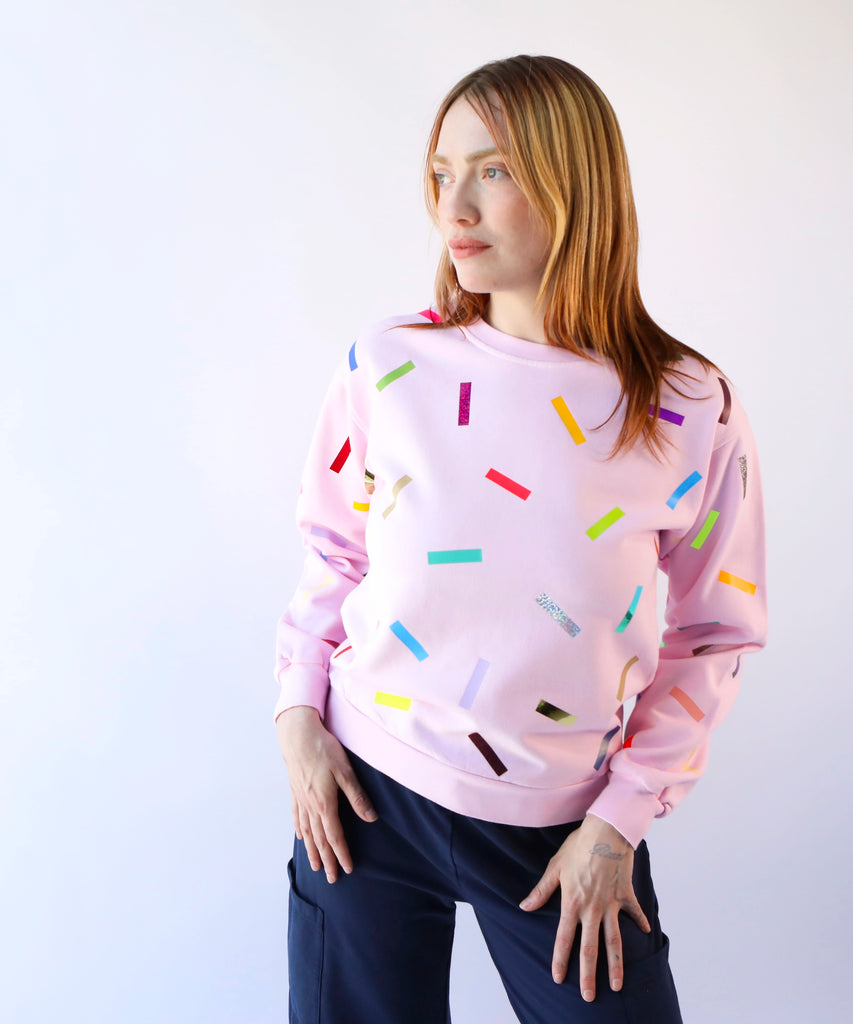 woman wearing a pink cotton sweatshirt with colorful sprinkles confetti pattern